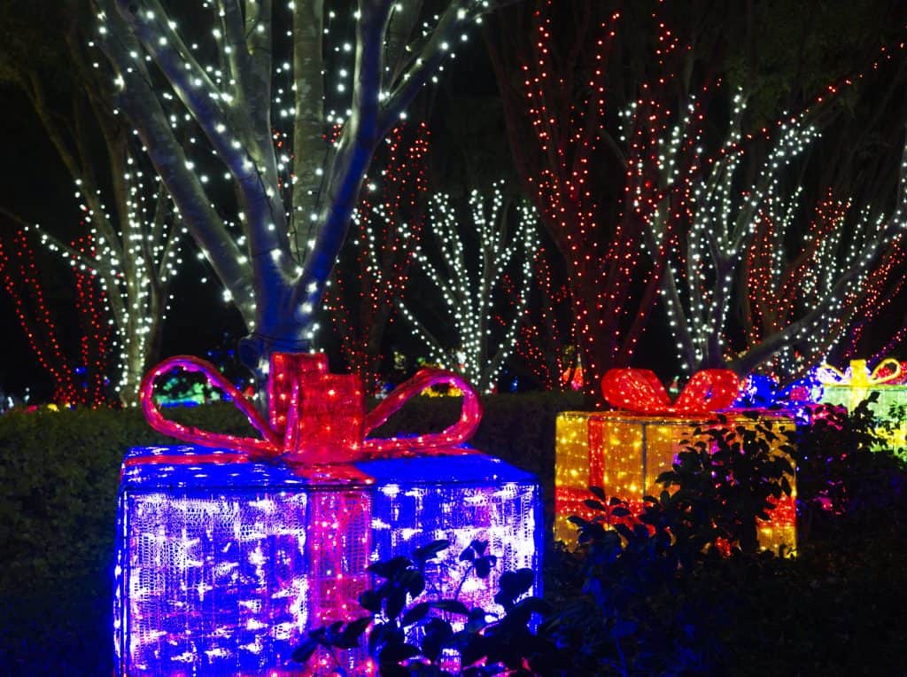Image of a series of wrapped christmas presents made of lights, lined up under trees filled with lights at Hunter Valley Gardens Christmas Lights Spectacular