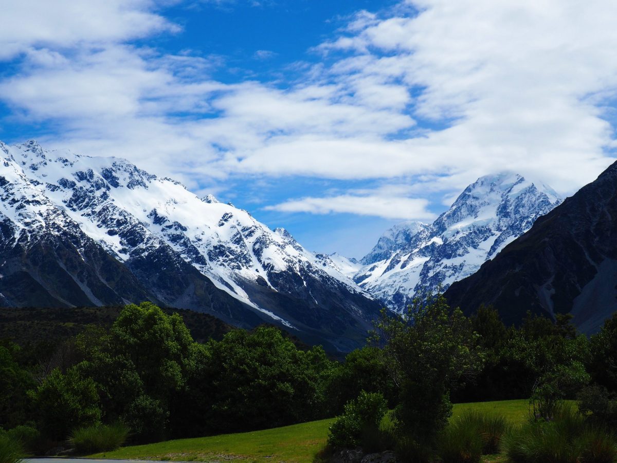 Snow capped mountains behind green fields near Mt Cook in New Zealand