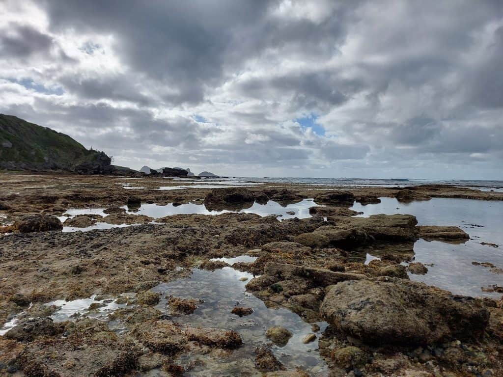 Image taken low looking across the rocks at Middle Beach on Lord Howe Island. The sky is reflected upon the pools of water in the rocks